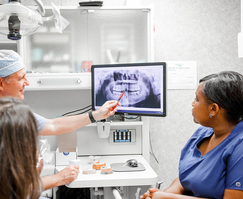 a dentist and dental hygienists reviewing an X-ray