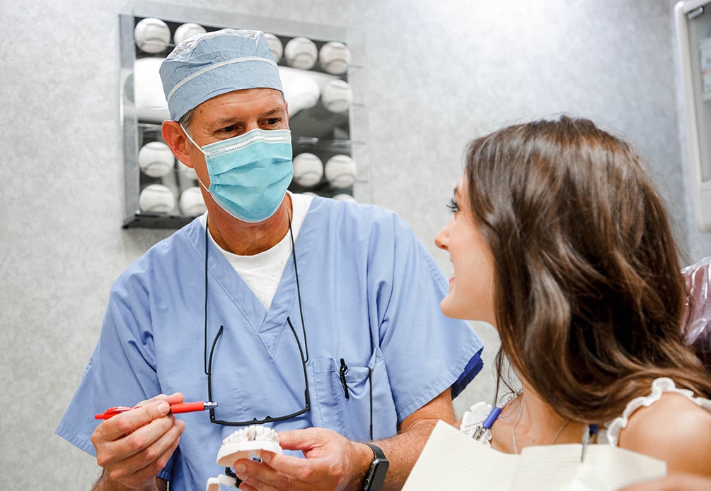 a dentist wearing a mask speaking with a patient